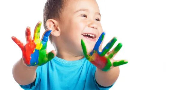 criança sorridente com mãos cheias de tinta